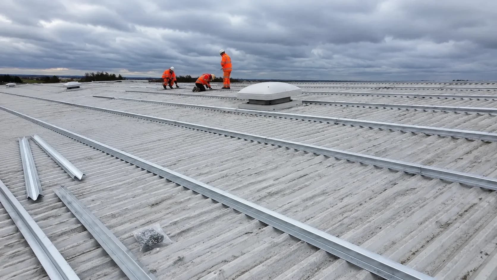 Industrial roofer installing metal roof cladding with insulation