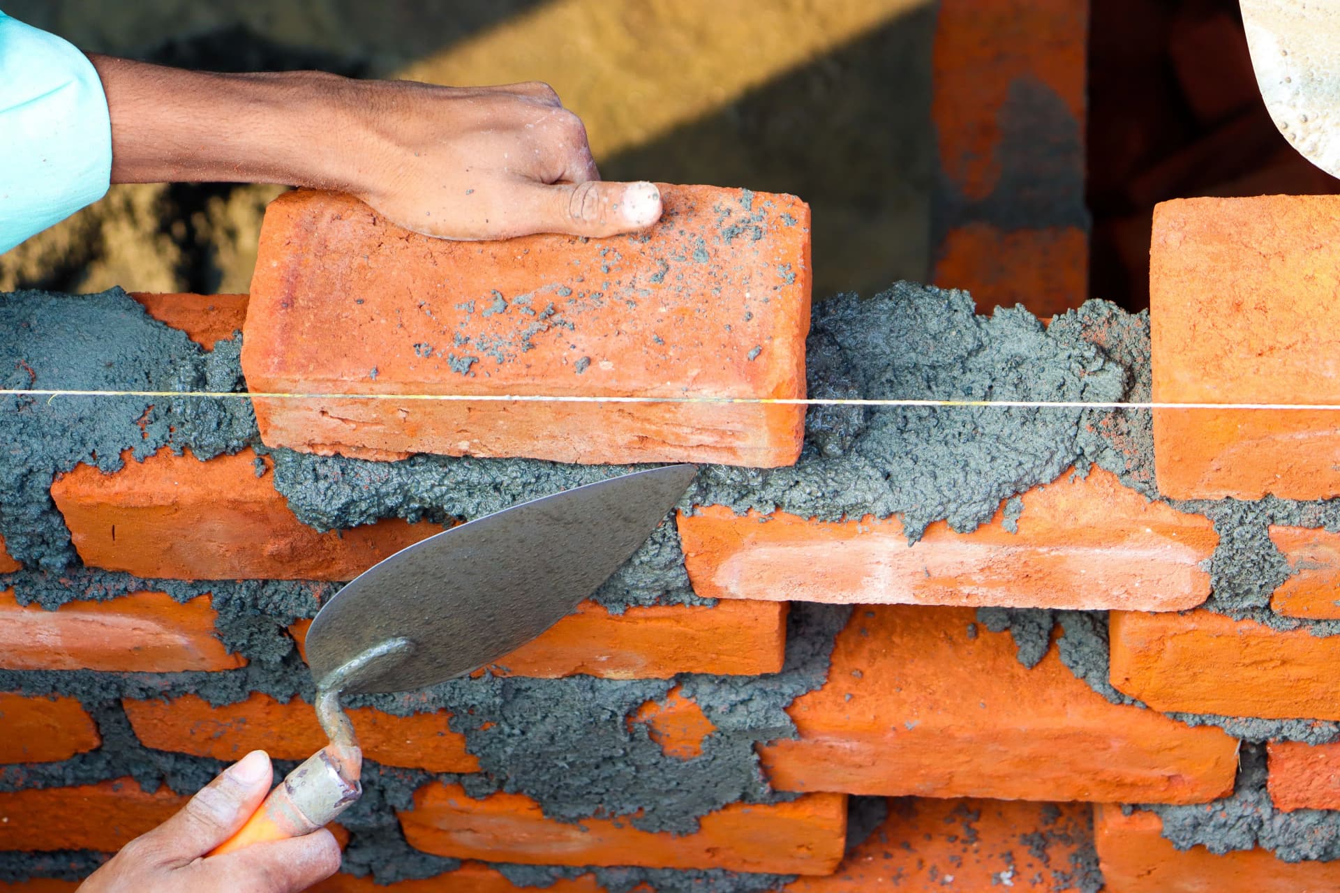 Hands carefully laying bricks with cement during precise masonry work.