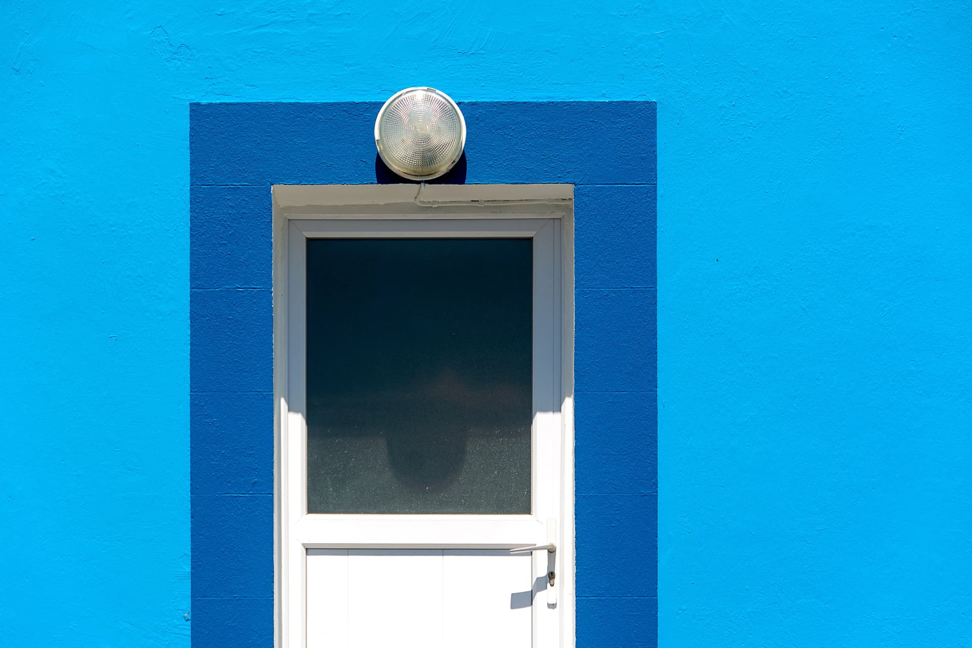 White door with dark blue trim set against a bright blue painted wall.