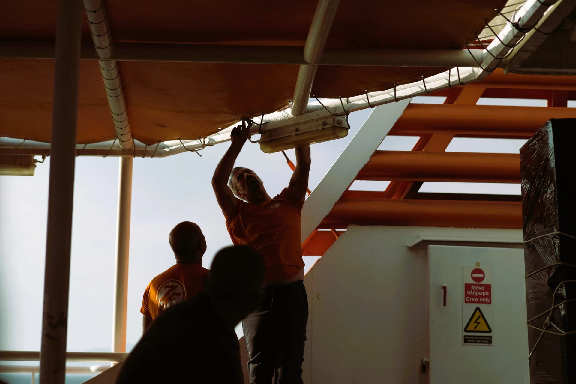Two workers installing and repairing emergency lighting systems