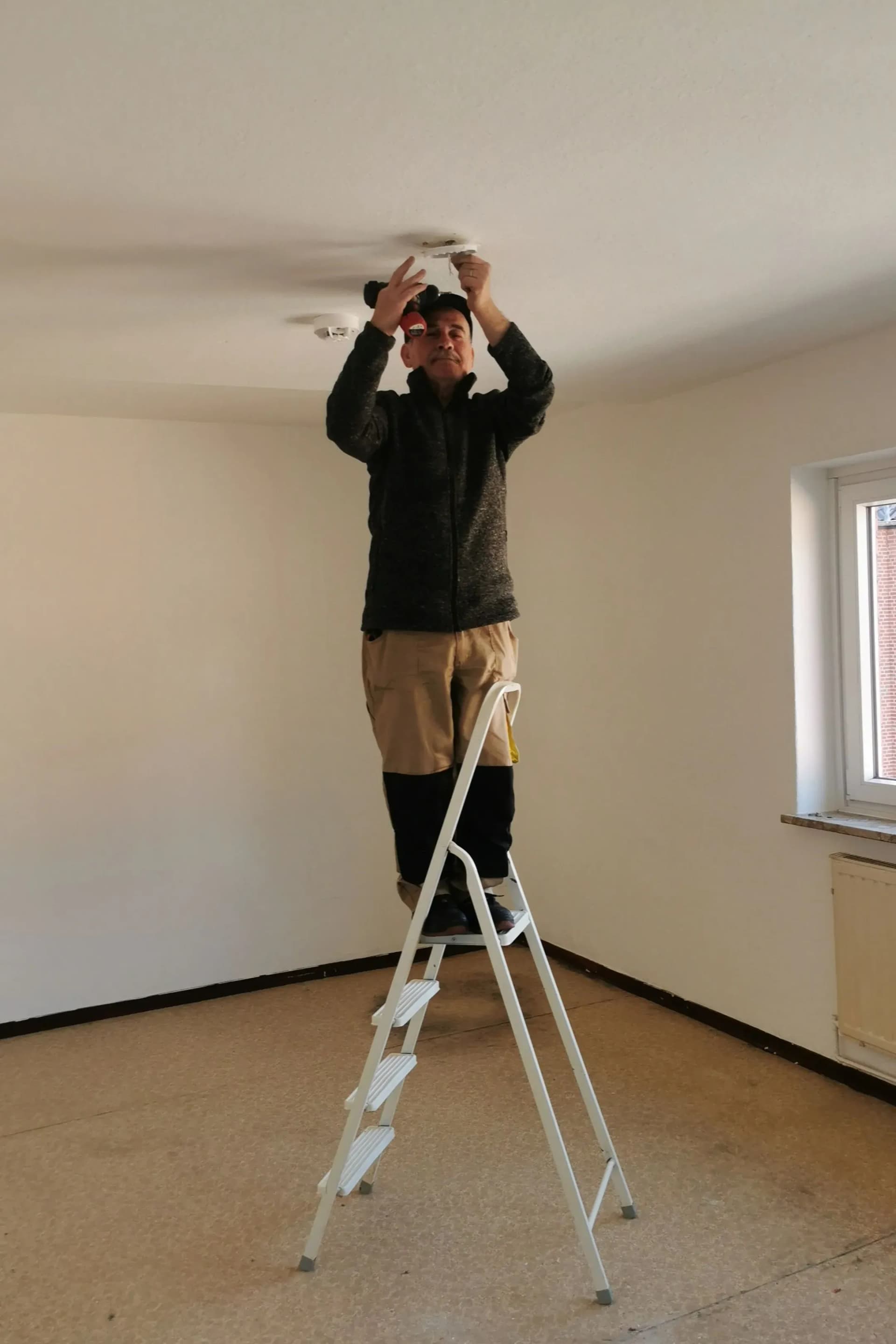 Worker inspecting a fire alarm during a fire risk assessment