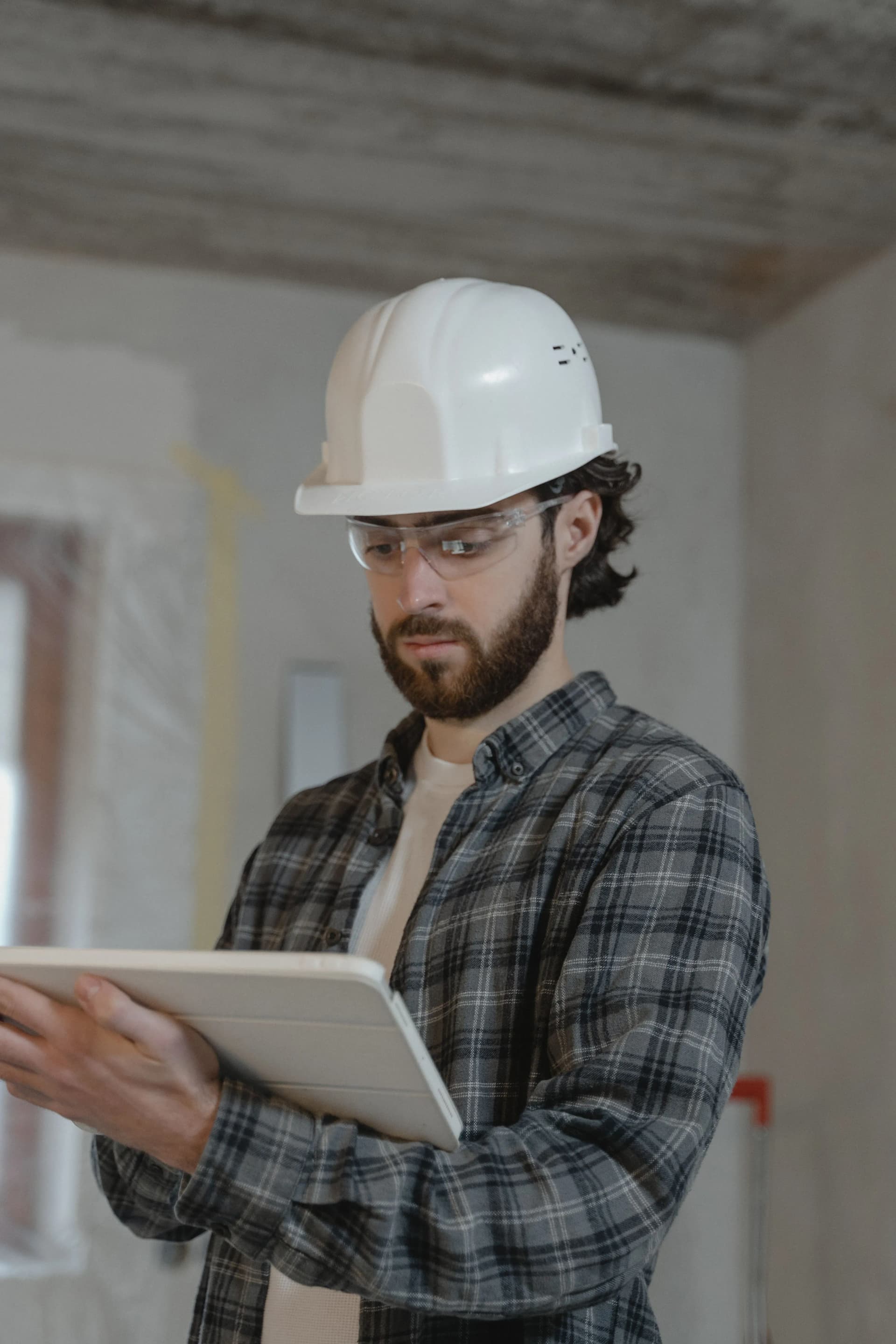 Worker reviewing fire risk assessment information on a tablet during remedial works