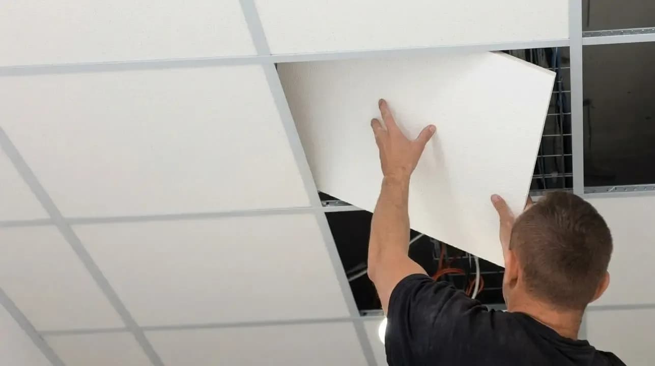 Worker carrying out floor and ceiling maintenance work in a commercial building.
