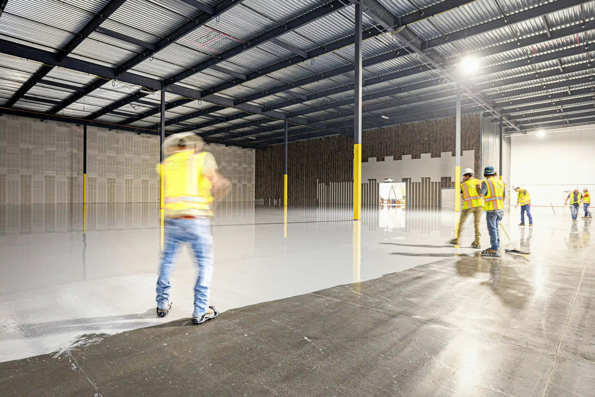 Worker applying industrial floor coating in a UK warehouse.