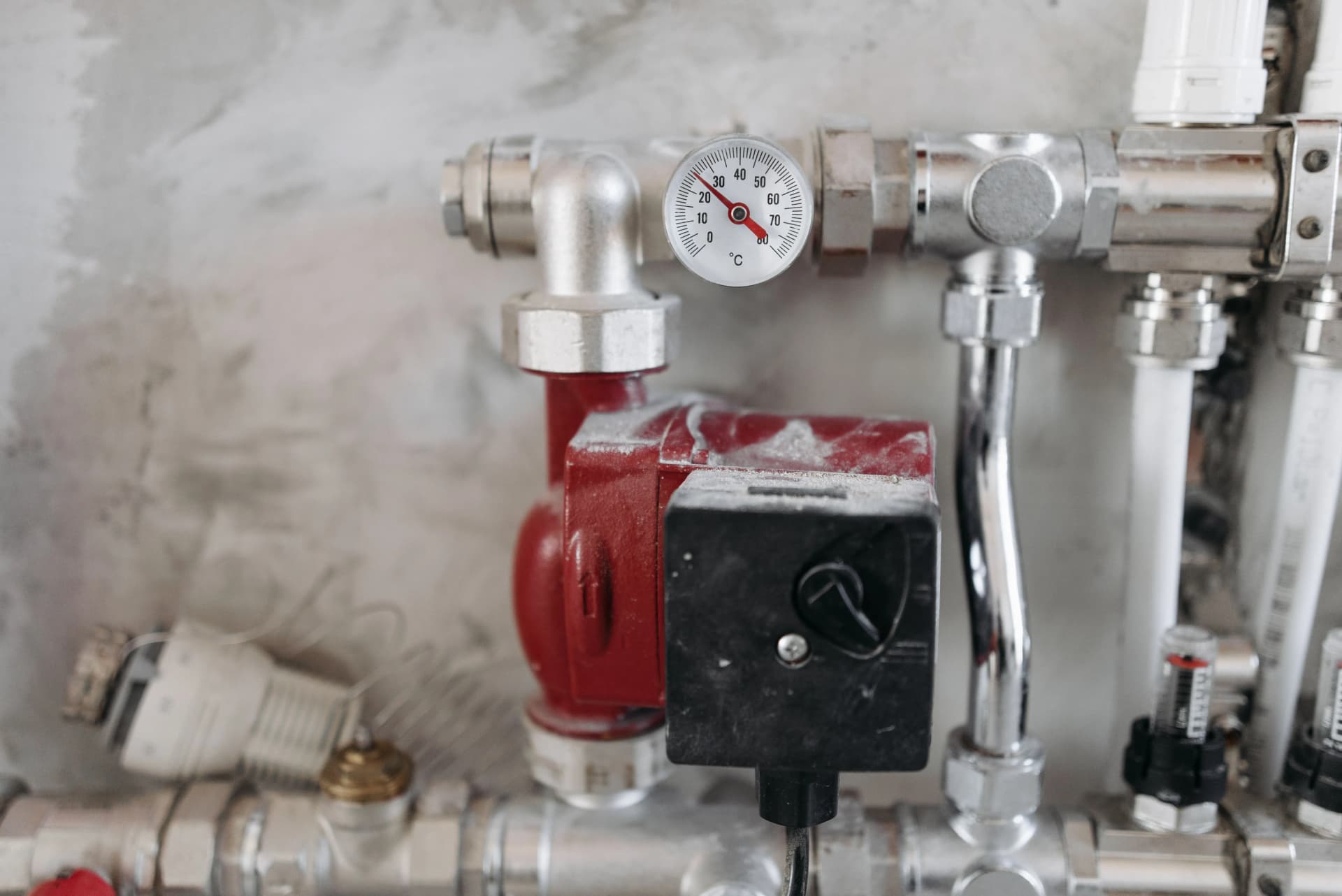 Close-up of an industrial plumbing system featuring a pressure gauge and steel pipes.
