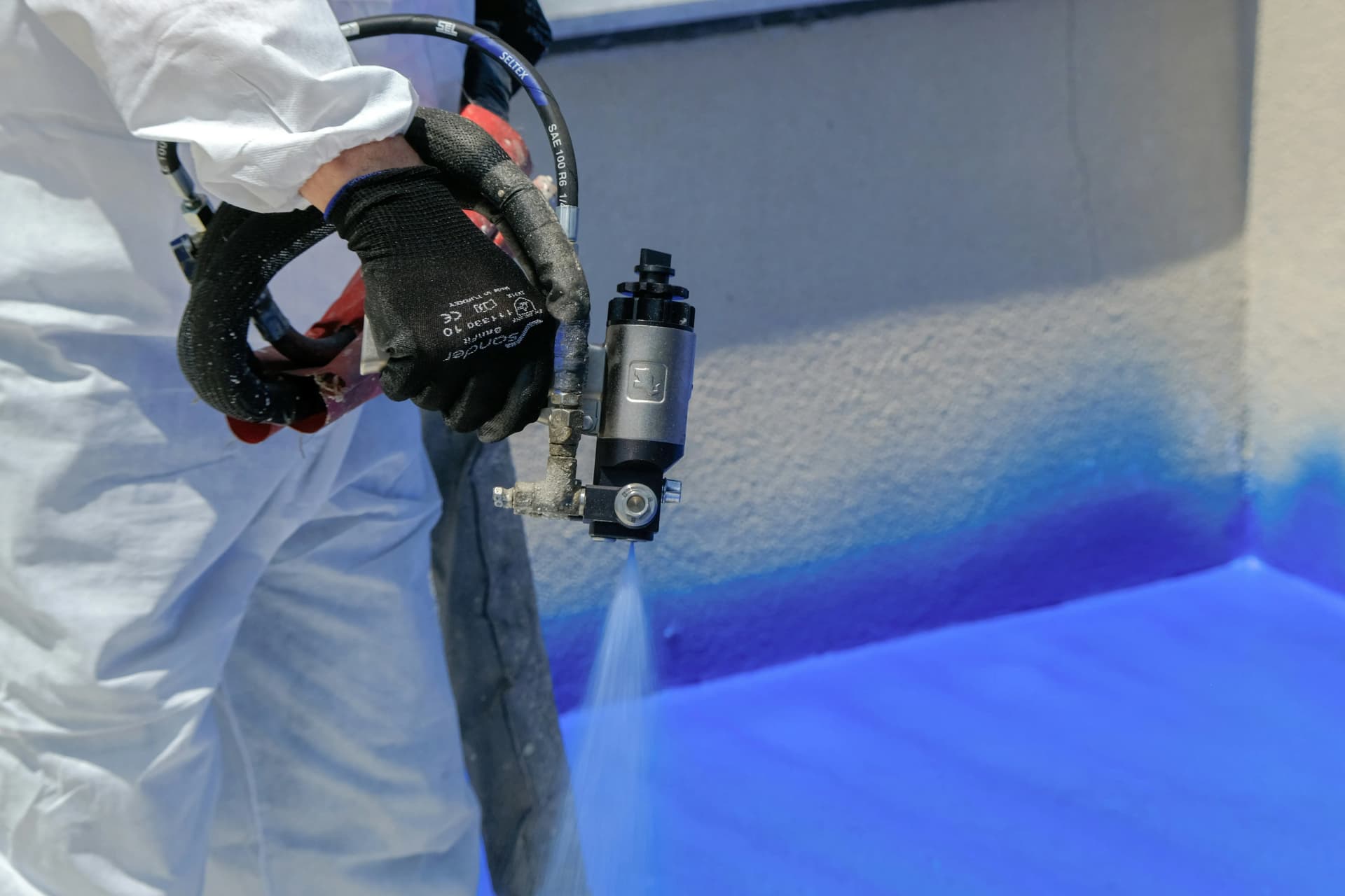 Professional contractors carrying out interior intumescent spraying within a UK commercial building to protect internal structural steelwork.