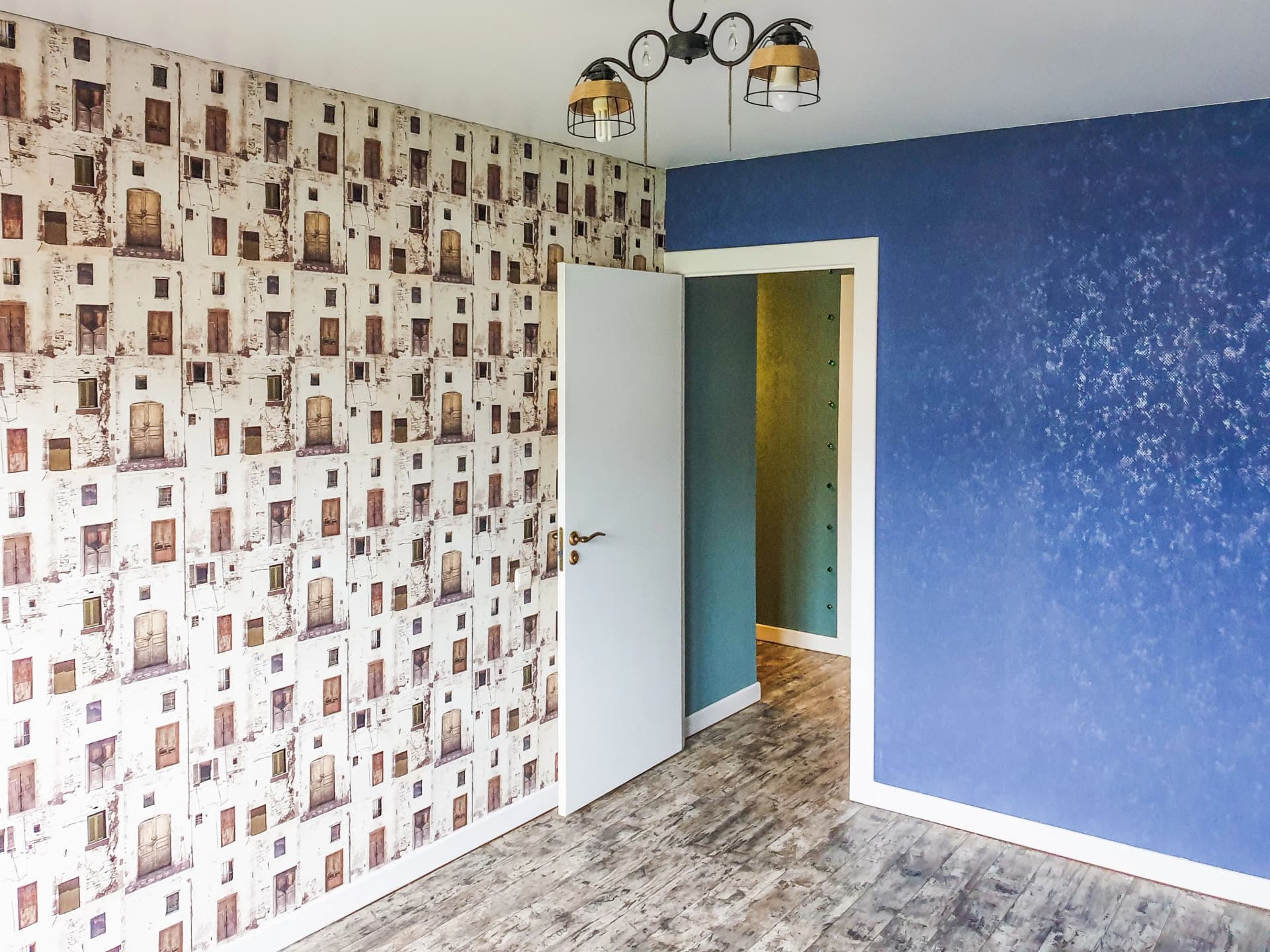 Room interior showcasing patterned building wallpaper alongside a textured blue accent wall and open white door.