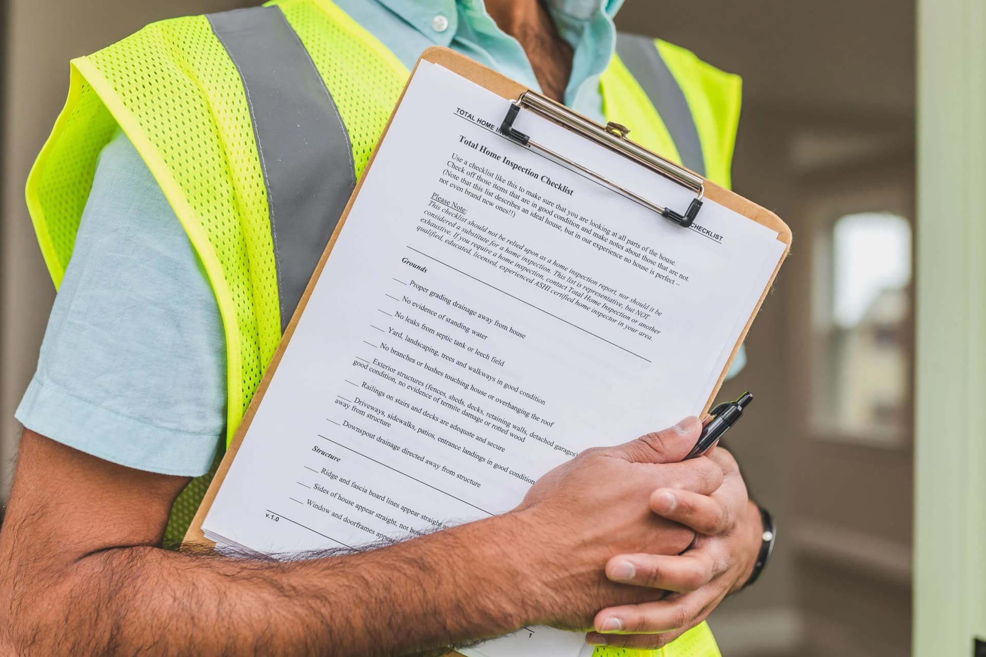Property inspector reviewing a checklist on a clipboard with a pen during a home inspection.