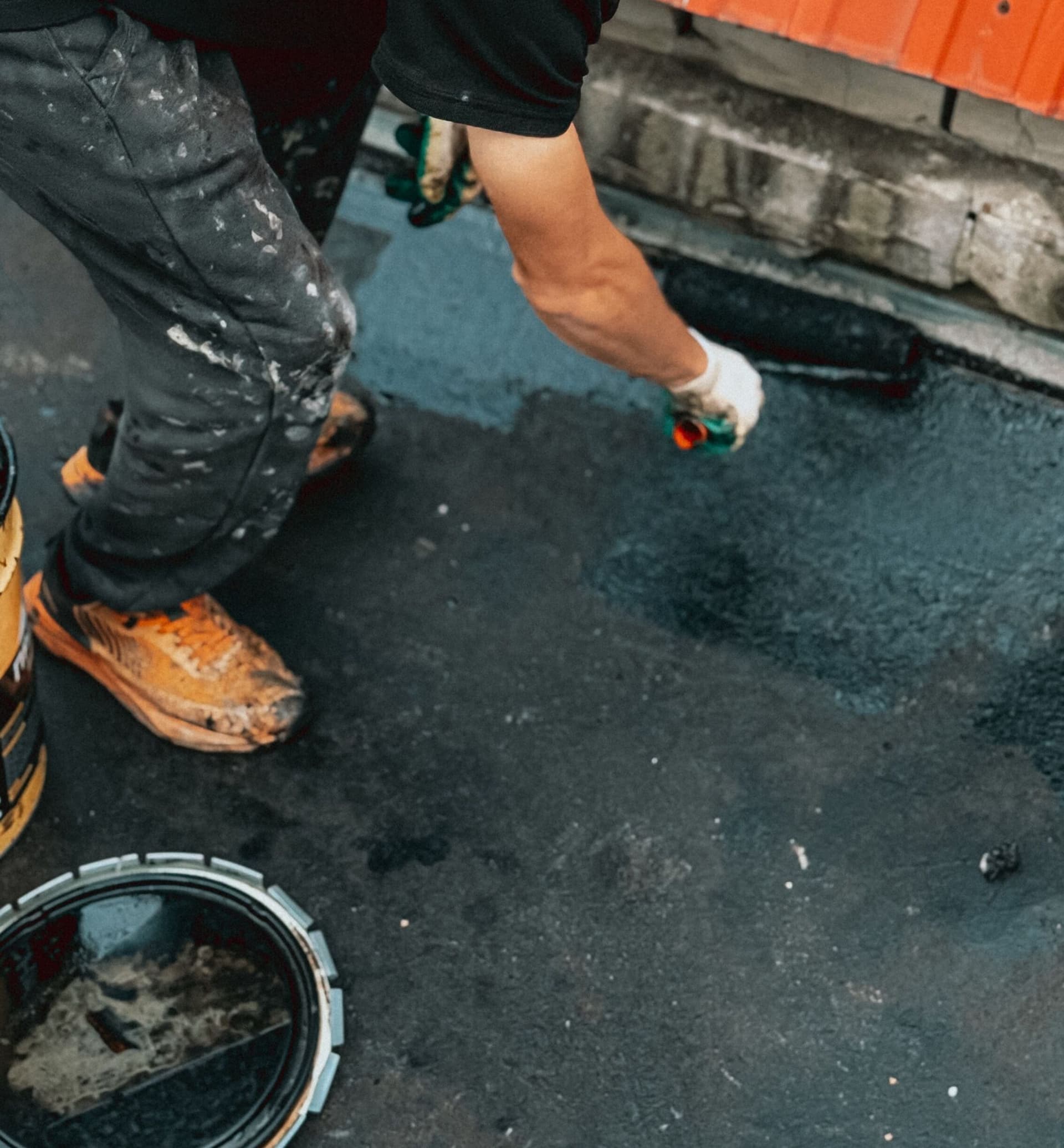 Worker preparing an industrial surface before coating in a UK plant facility.