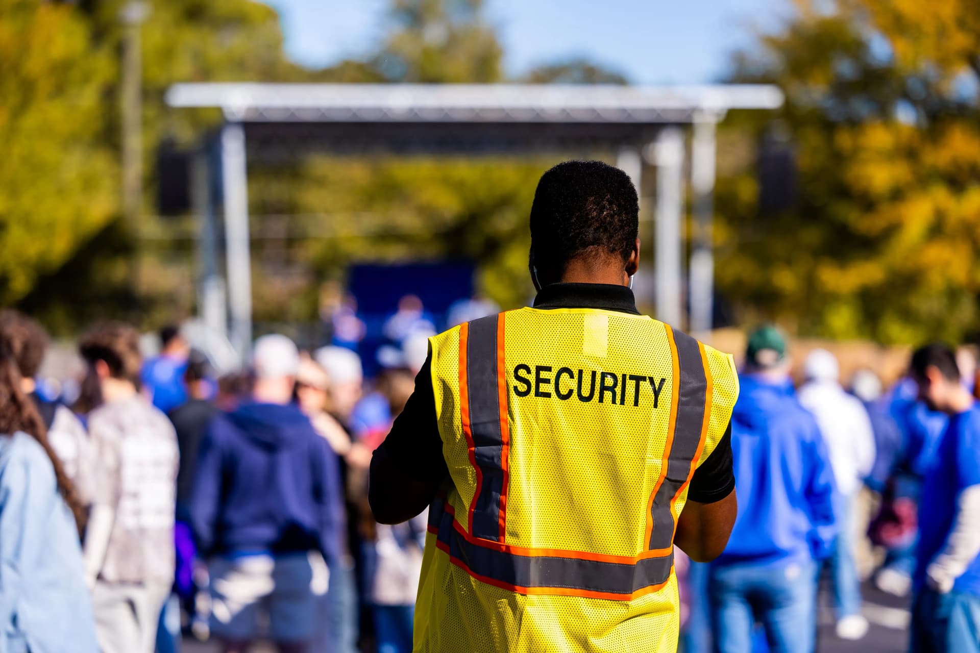 Security guard in a high-visibility vest monitoring a crowded outdoor event