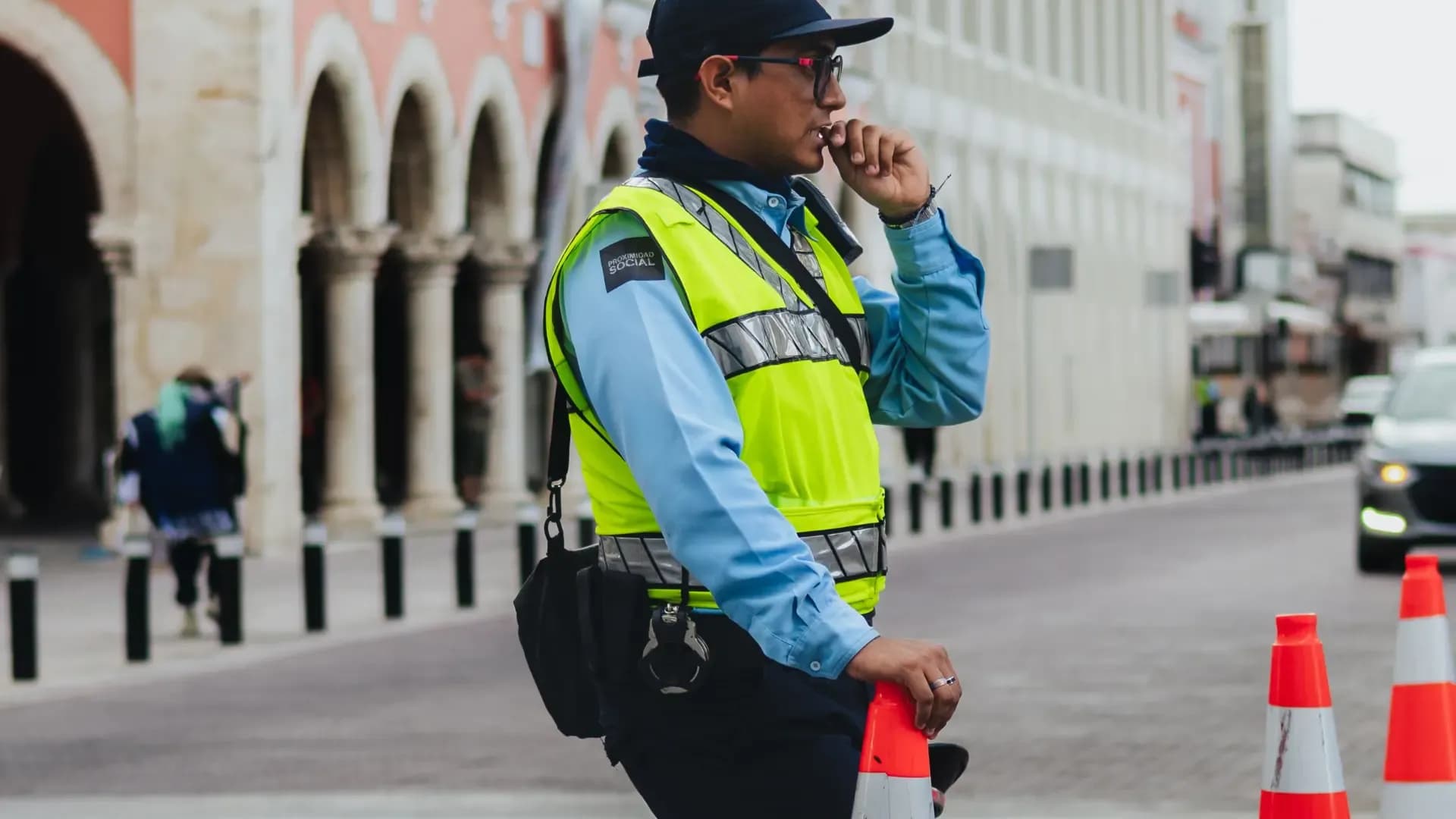 Security guard in a high-visibility vest managing safety on a public street